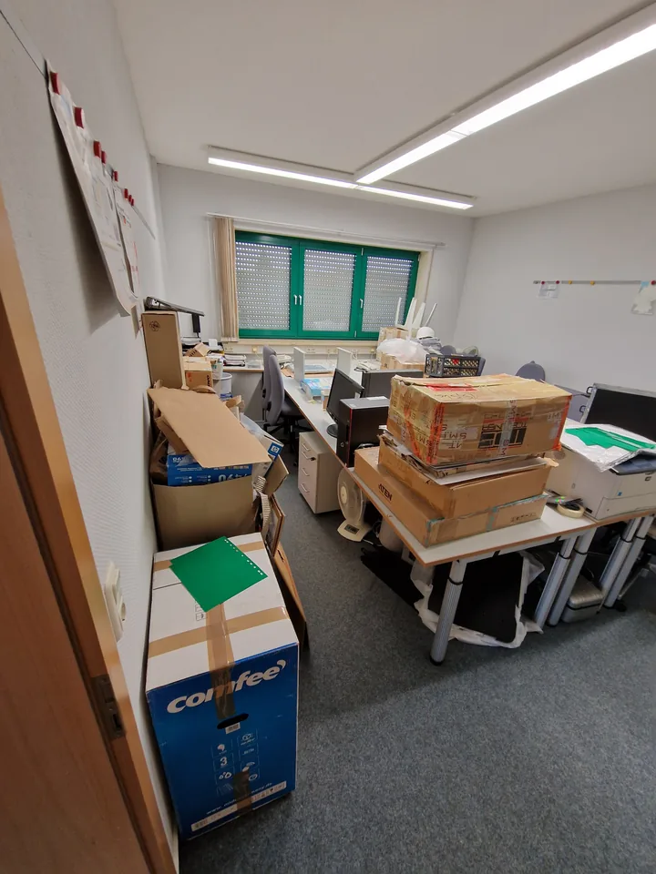 Büro mit gestapelten Kartons und Arbeitsplätzen vor der Teilräumung